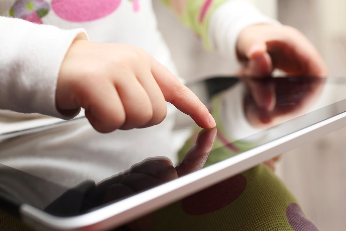 Young child using iPad device with pointer finger
