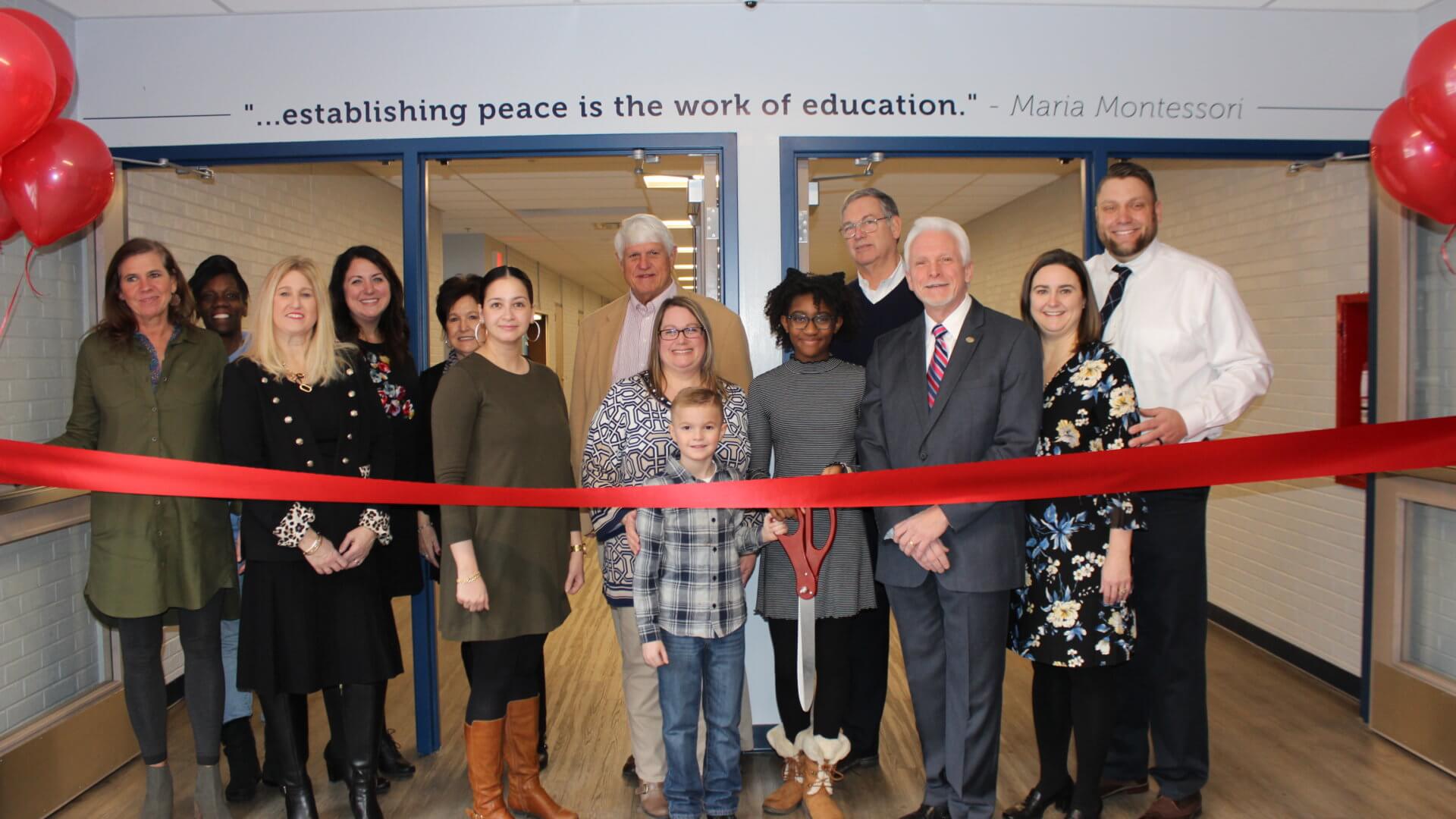 people standing in front of a large red ribbon