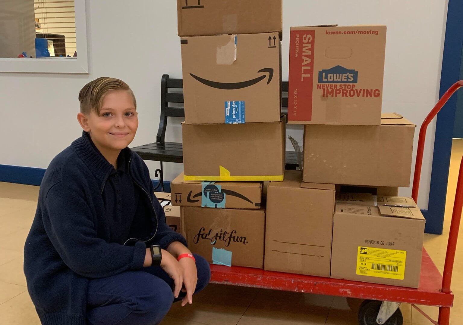 boy next to a cart of cardboard boxes