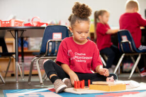 Creative Montessori Academy student poses for a picture in the classroom while she works on a project
