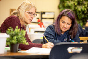 Creative Montessori Academy student works with a teacher on a project in the classroom