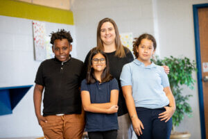 Interim Principal Gillon poses for a picture with 3 young Creative Montessori Academy students