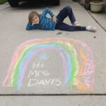student posing by rainbow chalk art